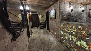 A hallway with stone walls, a wooden staircase, and a decorative wall panel.