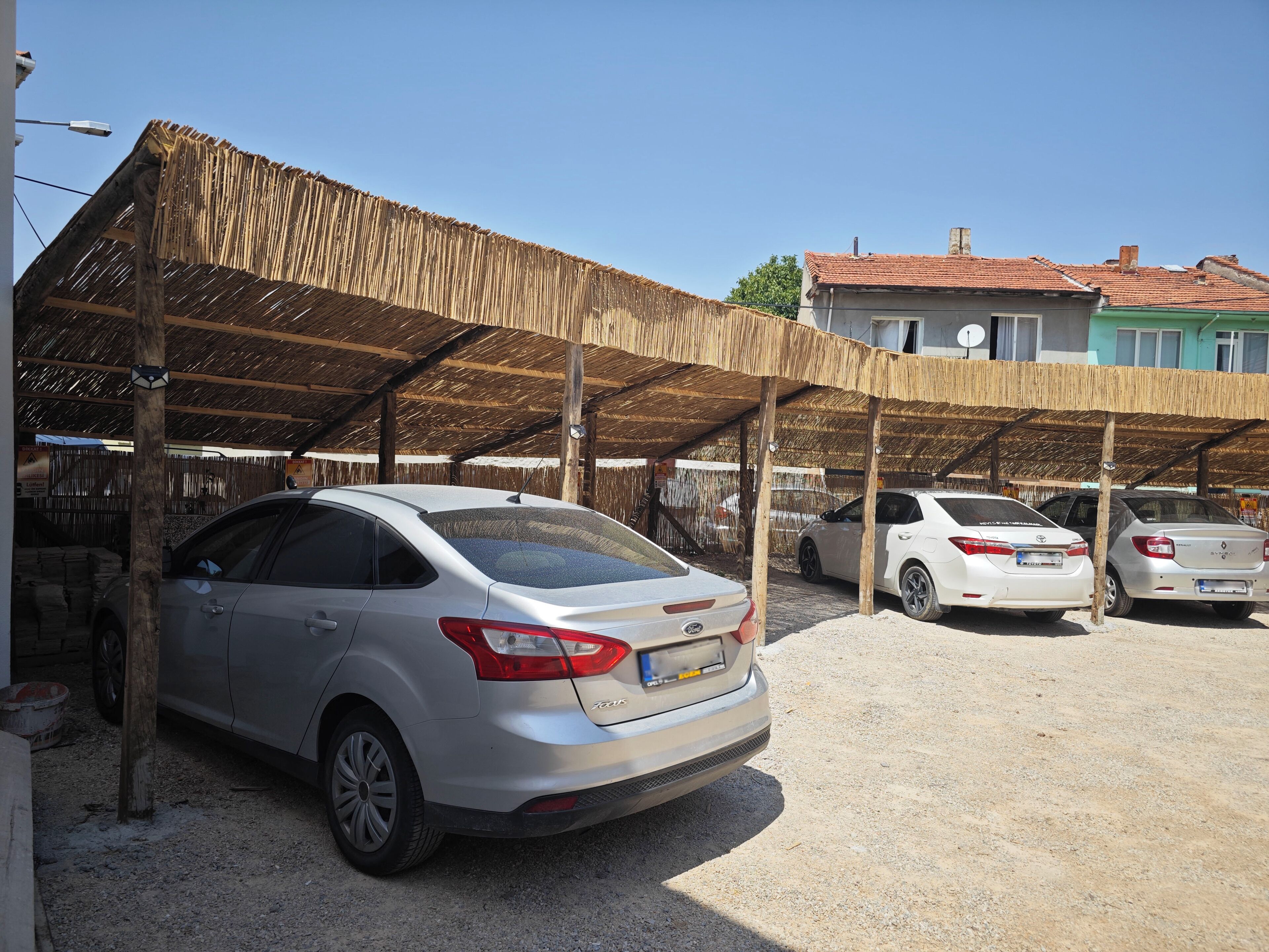 A parking area with cars under a thatched roof structure.