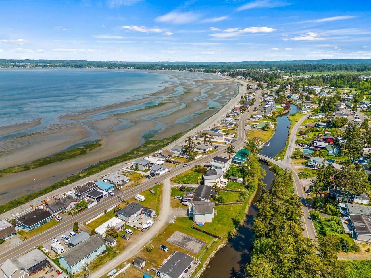 An aerial view of a coastal town with houses, roads, and a river.