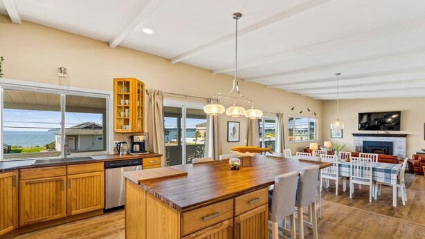 Una cocina amplia con armarios de madera, una isla central y una zona de comedor con chimenea.