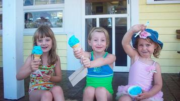 Trois enfants sont assis sur un porche, chacun tenant un cornet de glace.