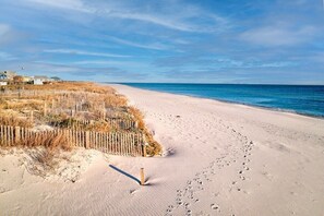A sandy beach with footprints leading to a wooden fence and houses in the background. - 5 BR House Pet Friendly | Epic View | Port of Yall (Baldwin County)