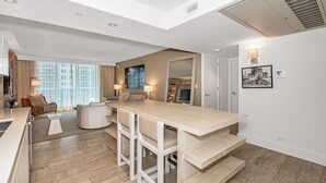 A modern kitchen with a central island, bar stools, and a dining area with a sofa and chairs. - 1 Hotel Modern King Suite 1BR 1 5BA w Ocean View (Miami Beach)