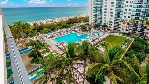 A hotel with a pool area, palm trees, and a view of the ocean. - 1 Hotel Modern King Suite 1BR 1 5BA w Ocean View (Miami Beach)