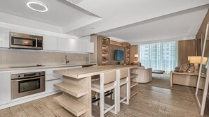 A modern kitchen with integrated appliances, a central island with bar stools, and a seating area with a sofa and lamp. - 1 Hotel Modern King Suite 1BR 1 5BA w Ocean View (Miami Beach)