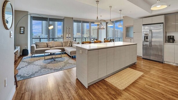 A modern kitchen with a central island, large windows, and a view of the city. - Luxury Waterfront Condo (Hallandale Beach)
