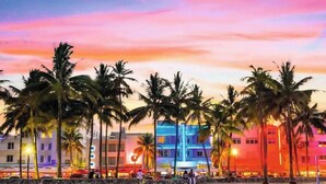A beachside hotel with palm trees and colorful buildings. - Luxury Waterfront Condo (Hallandale Beach)