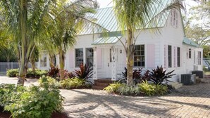 A white building with a green roof, surrounded by palm trees and various plants. - THE FAMILY REUNION COMPOUND AT OLD COLORADO INN (Stuart)