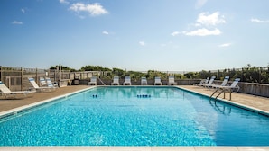 A rectangular swimming pool with clear blue water, surrounded by a wooden deck and metal fencing.
