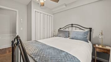 Une chambre à coucher avec un lit, une tête de lit en bois, une table de chevet avec une lampe et une armoire.