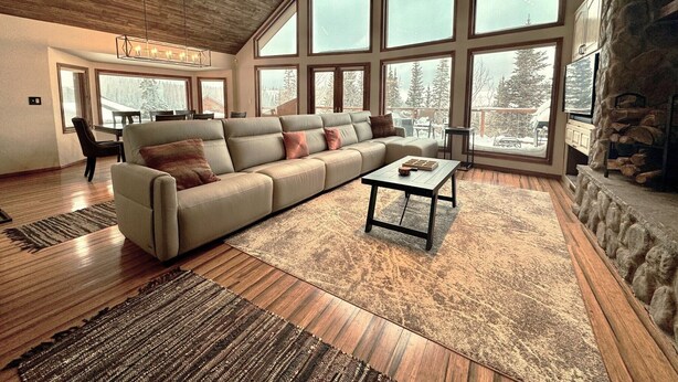 A spacious living room with a large sectional sofa, a coffee table, and a stone fireplace. - Mountain Cabin w/VIEWS in Brian Head, Utah! Fun to be had Winter, Summer & Fall! (Brian Head)