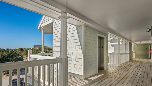 A covered wooden deck with white railings, a clear sky, and a view of the surrounding area. - *New*Oceanview, Golf, Pool, Tennis, Beach Access (Corolla)