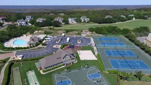 An aerial view of a residential area with a swimming pool, tennis courts, and a building with a red roof. - *New*Oceanview, Golf, Pool, Tennis, Beach Access (Corolla)