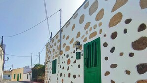 Une rue bordée d’un immeuble dont la façade blanche est percée de grandes ouvertures de formes irrégulières.