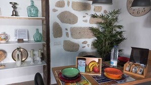 Un coin repas avec une table en bois, des assiettes colorées, un saladier de fruits et une plante en pot.