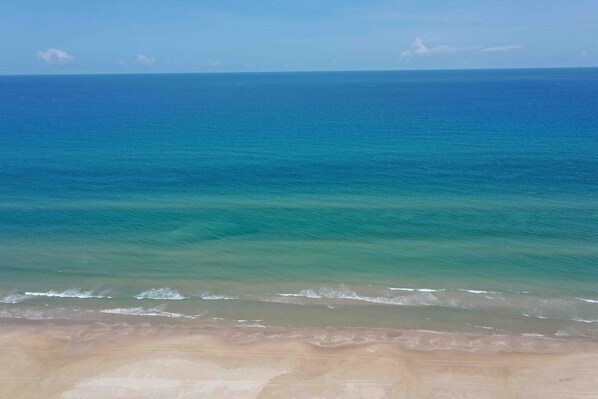 A beach with clear blue water and a sandy shore.