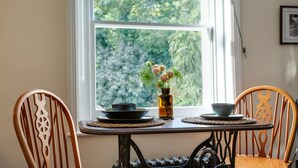 A dining table with two chairs, a vase with flowers, and two bowls. - Beautiful apartment in central Bath (Bath)