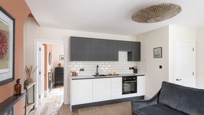 A modern kitchen with white cabinets, a black countertop, and a built-in oven. - Beautiful apartment in central Bath (Bath)