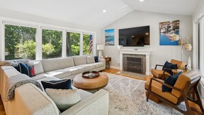 A modern living room with a large window, a fireplace, a television, and a sofa.