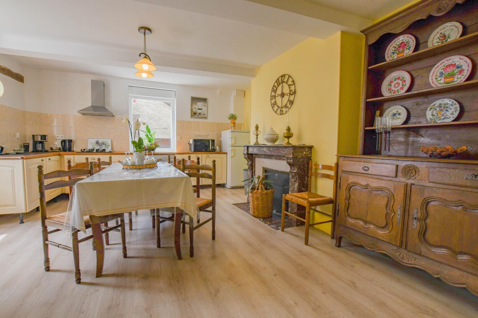 A dining area with a table set for four, a fireplace, and a shelf with decorative plates.