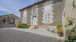 A building with a gravel driveway, a bench, and a potted plant.