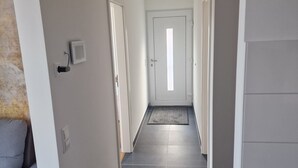 A hallway with a tiled floor, a grey sofa, and a door at the end. - Im Stadtzentrum, in der Nähe von Musikschulen (Trossingen)