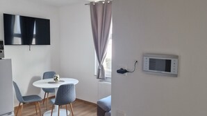 A modern kitchen with a white refrigerator, a built-in oven, and a microwave. There is a dining area with a round table and four chairs. - Im Stadtzentrum, in der Nähe von Musikschulen (Trossingen)