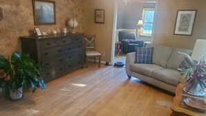 A living room with a sofa, a wooden cabinet, a chair, and a potted plant. - 3 bedroom/2 bath home; close to EAA. Large kitchen and outside deck area  (Oshkosh)