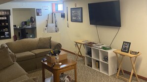 A living room with a sofa, a coffee table, a TV, and a bookshelf. - 3 bedroom/2 bath home; close to EAA. Large kitchen and outside deck area  (Oshkosh)
