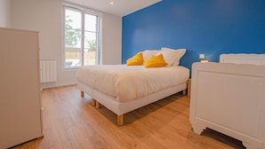 Une chambre à coucher avec un lit, une fenêtre et une commode blanche.