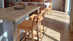 Un coin repas avec une table et des chaises en bois, un luminaire suspendu et un meuble en bois à l’arrière-plan.