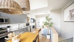 Eine moderne Küche mit grauen Schränken, einem Holztisch und Korbtreleuchten.