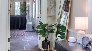 A hallway with a stone wall, a mirror, a lamp, and a wooden floor. - Stone Cottage at Roundtop Estate couples Retreat (Wrightsville)