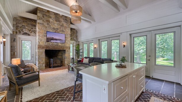 A spacious living area with a stone fireplace, large windows, and a cozy seating arrangement. - Stone Cottage at Roundtop Estate couples Retreat (Wrightsville)