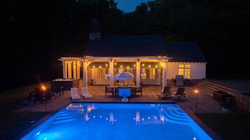 A poolside area with a covered patio, outdoor furniture, and string lights.