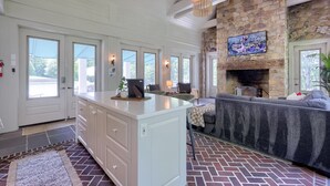 A spacious living area with a stone fireplace, a large island with a flat surface, and a comfortable seating area. - Stone Cottage at Roundtop Estate couples Retreat (Wrightsville)