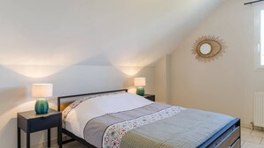 Ein Schlafzimmer mit einem Bett, zwei Nachttischen, einer Wanddekoration mit Sonnenelementen und einem Fenster.