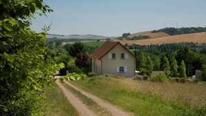 Ein Haus mit einem Feldweg, umgeben von Grünflächen und Feldern.