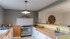 Eine moderne Küche mit Gasherd, Backofen und einer großen Wanduhr.