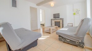 Une chambre avec deux lits simples, une télévision, une cheminée et une petite table.
