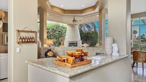 A kitchen with a large island, a ceiling fan, and a view of the outdoors.