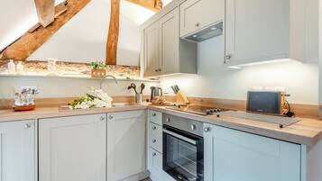 Una cocina moderna con horno empotrado, encimera de madera y lámpara colgante.