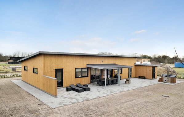 A modern building with a wooden facade, a covered outdoor seating area, and a small adjacent structure.