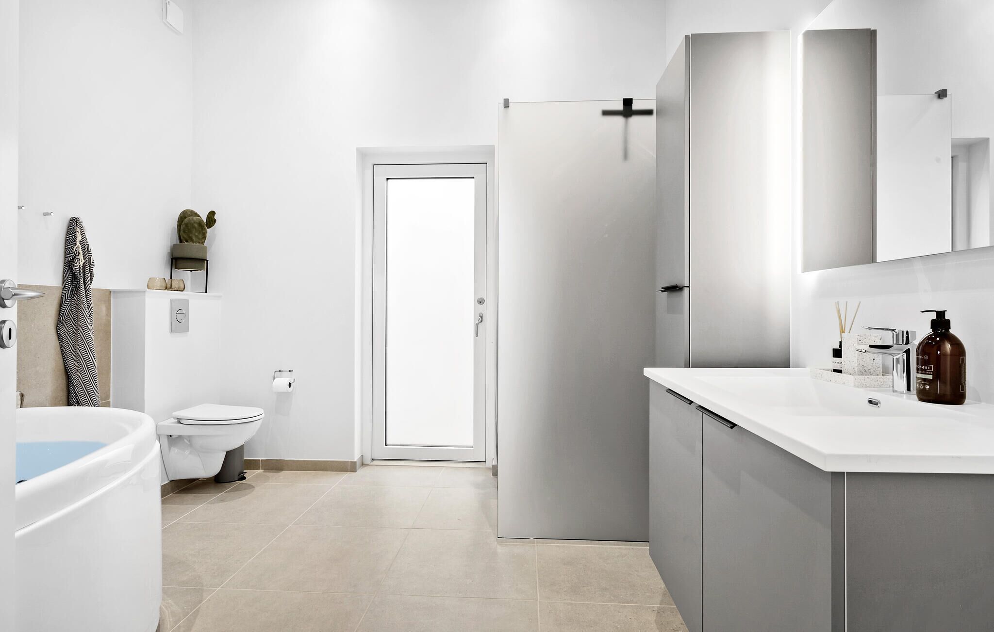 A modern bathroom with a toilet, bidet, and a sink with a mirror above it.