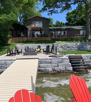Une terrasse avec des fauteuils Adirondack, une petite piscine et un mur en pierre.