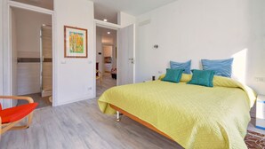 Ein Schlafzimmer mit einem großen Bett, einem Sessel und einer Tür zu einem Badezimmer.