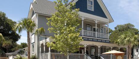 A two-story house with a balcony, a porch, and a small garden area.