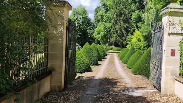 A pathway leading through a well-maintained garden with a gated entrance. - T2 Climatisé Dans le Parc du Castel Silence, 900m de la Plage Port D'envaux (Port-d'Envaux)