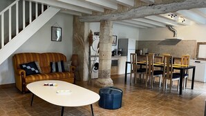 A spacious living area with a sofa, coffee table, and dining table set. A staircase leads to an upper level. - T2 Climatisé Dans le Parc du Castel Silence, 900m de la Plage Port D'envaux (Port-d'Envaux)