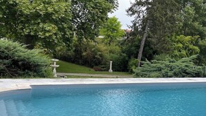 A swimming pool with a stone border, surrounded by lush greenery and trees. - T2 Climatisé Dans le Parc du Castel Silence, 900m de la Plage Port D'envaux (Port-d'Envaux)